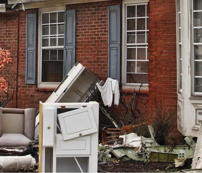 damaged furniture and other home items sitting outside of red brick 