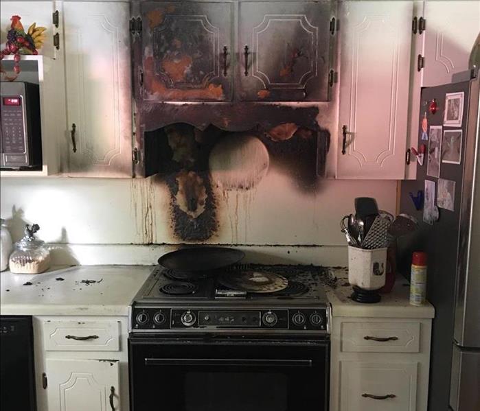 A burned mark on the cabinet over the stove.