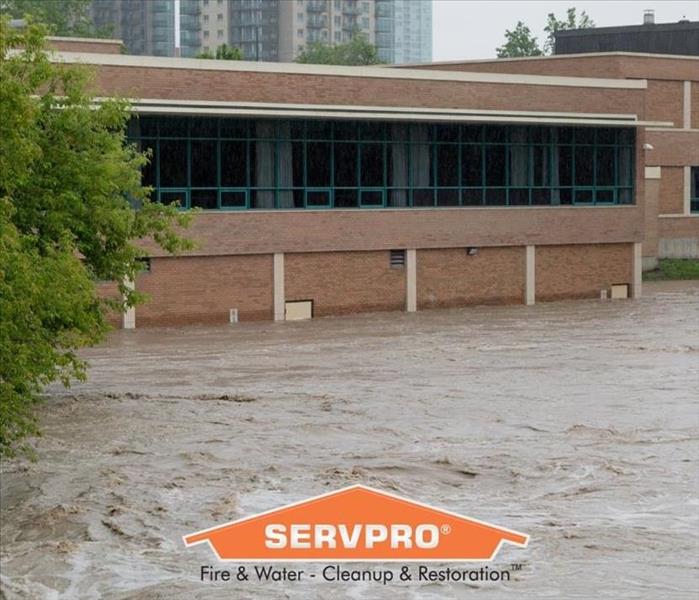 Brick building surrounded by flood water with a SERVPRO logo